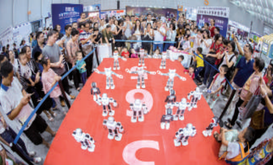 “互聯網+”博覽會展館內，市民圍觀跳集體舞的機器人。/珠江商報記者資料圖（記者周焯杰攝）